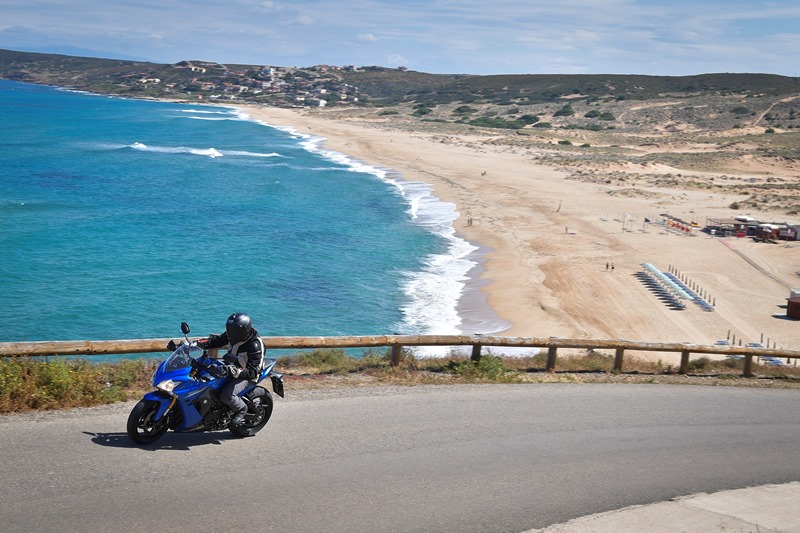 moto su strada con sfondo mare e spiaggia